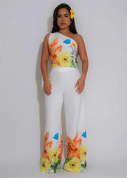 Woman wearing a floral top and white pants with a gray background