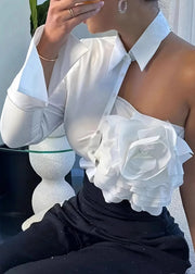 Person wearing a white floral top and black pants with a blurred background