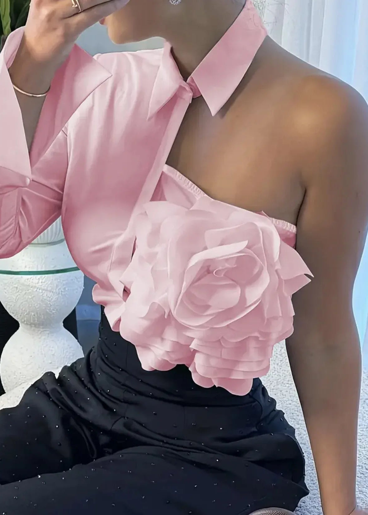 Person wearing a pink one-shoulder top with a large floral design.