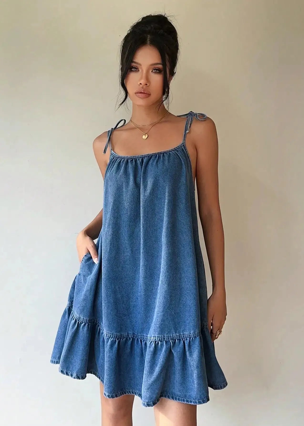 Woman wearing a blue denim dress against a plain background