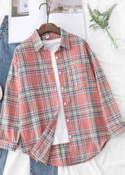 Plaid shirt on a hanger with jeans and a plant in the background