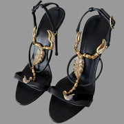 Black sandals with gold and crystal embellishments on a light background