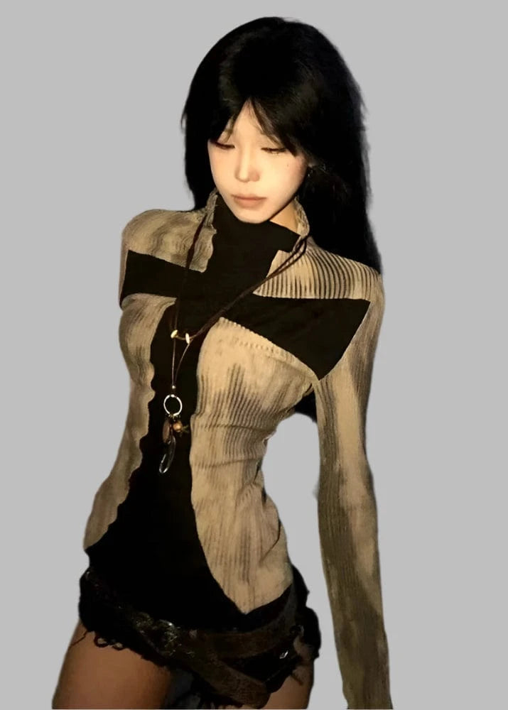Woman wearing a beige cardigan over a black top and shorts against a tiled wall.