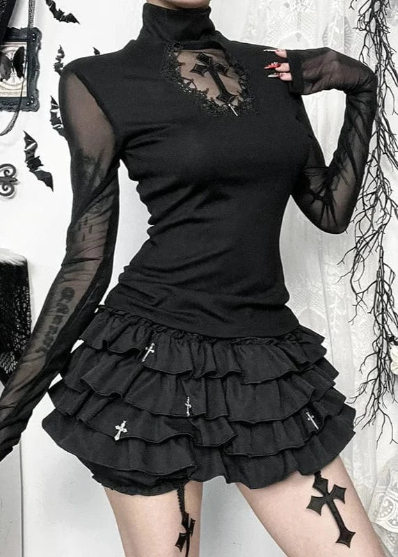 Person wearing a black gothic outfit with ruffled skirt and sheer sleeves in a decorative setting.