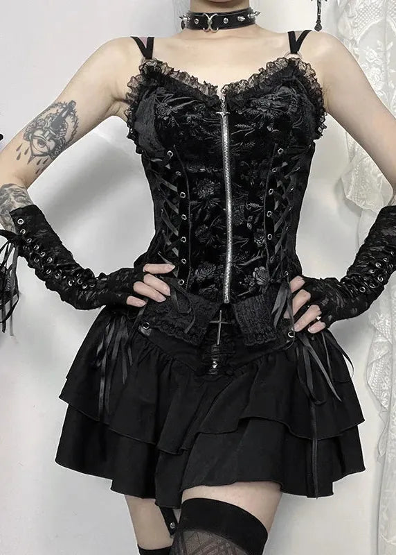 Person wearing a black lace corset and skirt with gloves against a white background