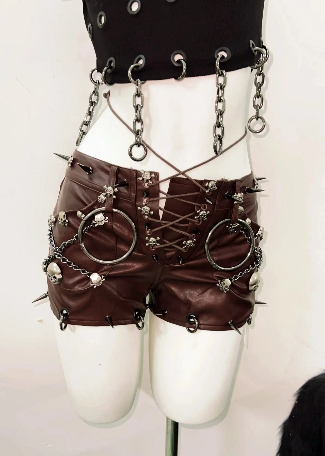 Steampunk-style outfit with leather shorts, chains, and spikes on a mannequin against a white background.