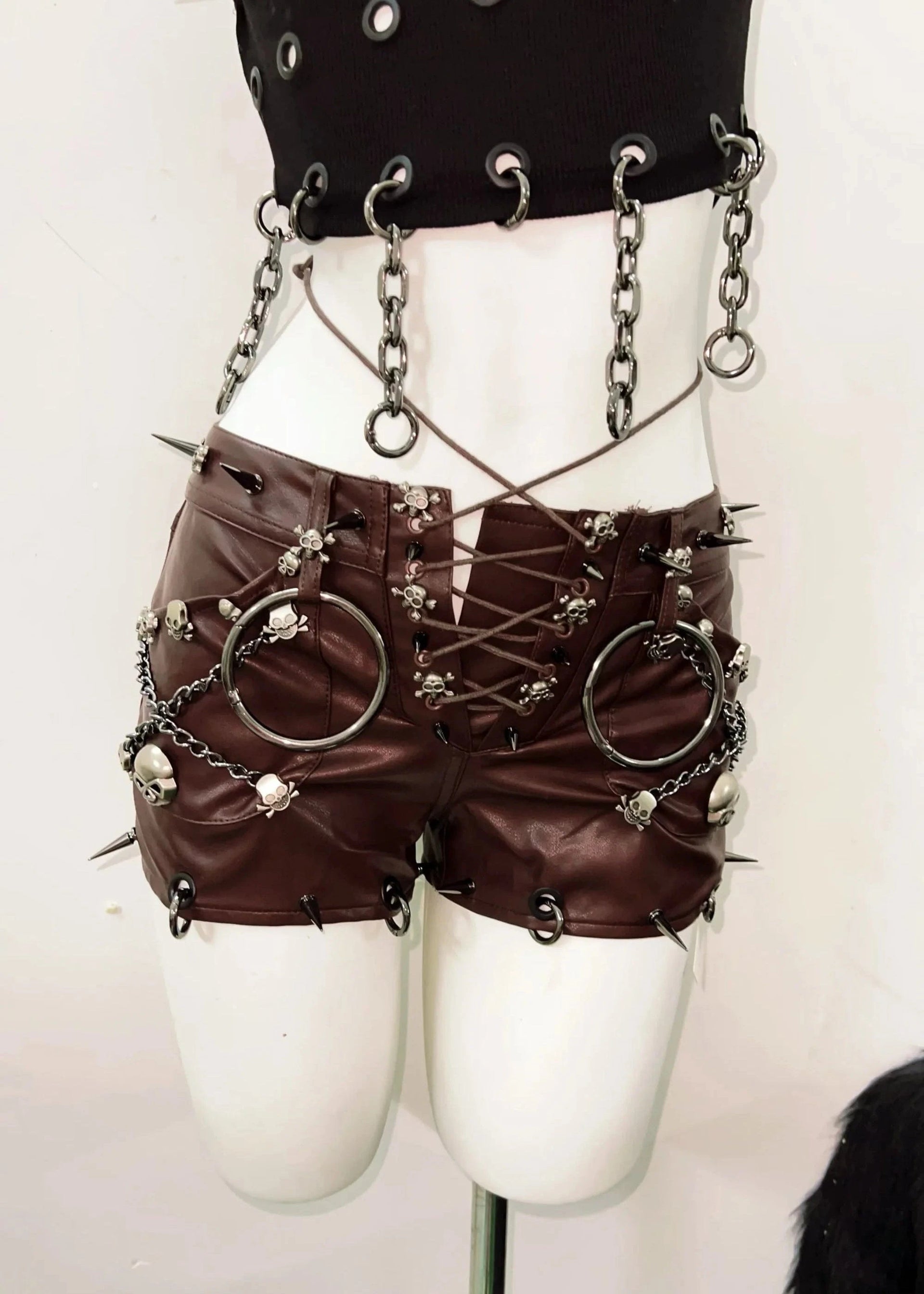 Steampunk-style outfit with leather shorts, chains, and spikes on a mannequin against a white background.