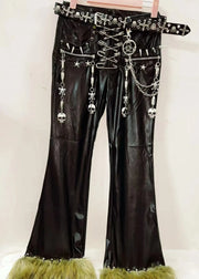 Black leather pants with decorative elements and green fringes on a white background