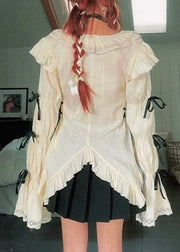 Person wearing a white ruffled blouse and black skirt in a room with furniture and decor.