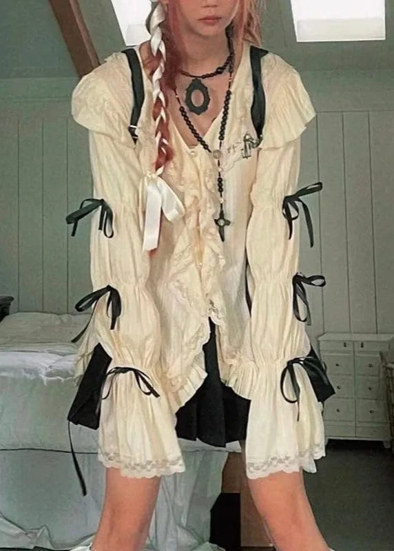 Person wearing a white lace outfit with black ribbons in a room.