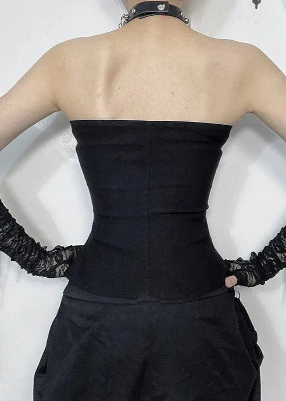 Person wearing a black strapless top and high-waisted pants with lace gloves on a white background