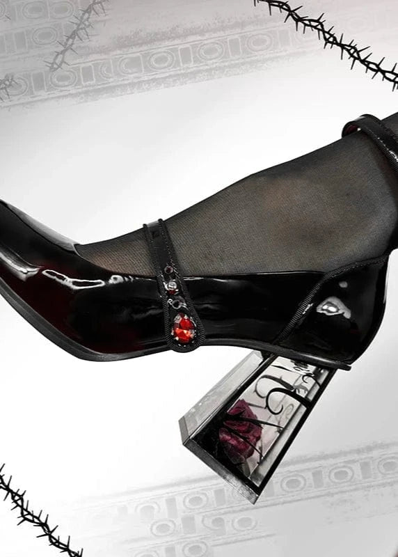 Black high-heeled shoe with red embellishments on a white background