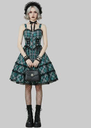 Woman wearing a green plaid dress with a plain background