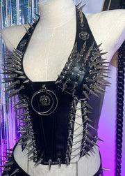 Black leather garment with spikes on a mannequin against a colorful background