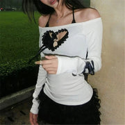 Woman wearing a white off-shoulder top with black heart design and a black skirt.