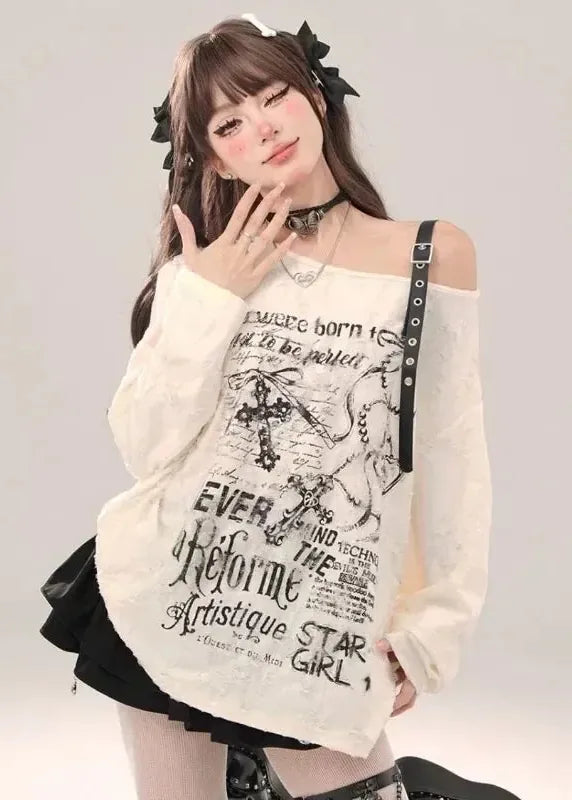 Person wearing a white oversized sweater with text and graphics, standing against a plain background