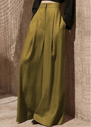 Person wearing olive green wide-leg pants against a textured wall.