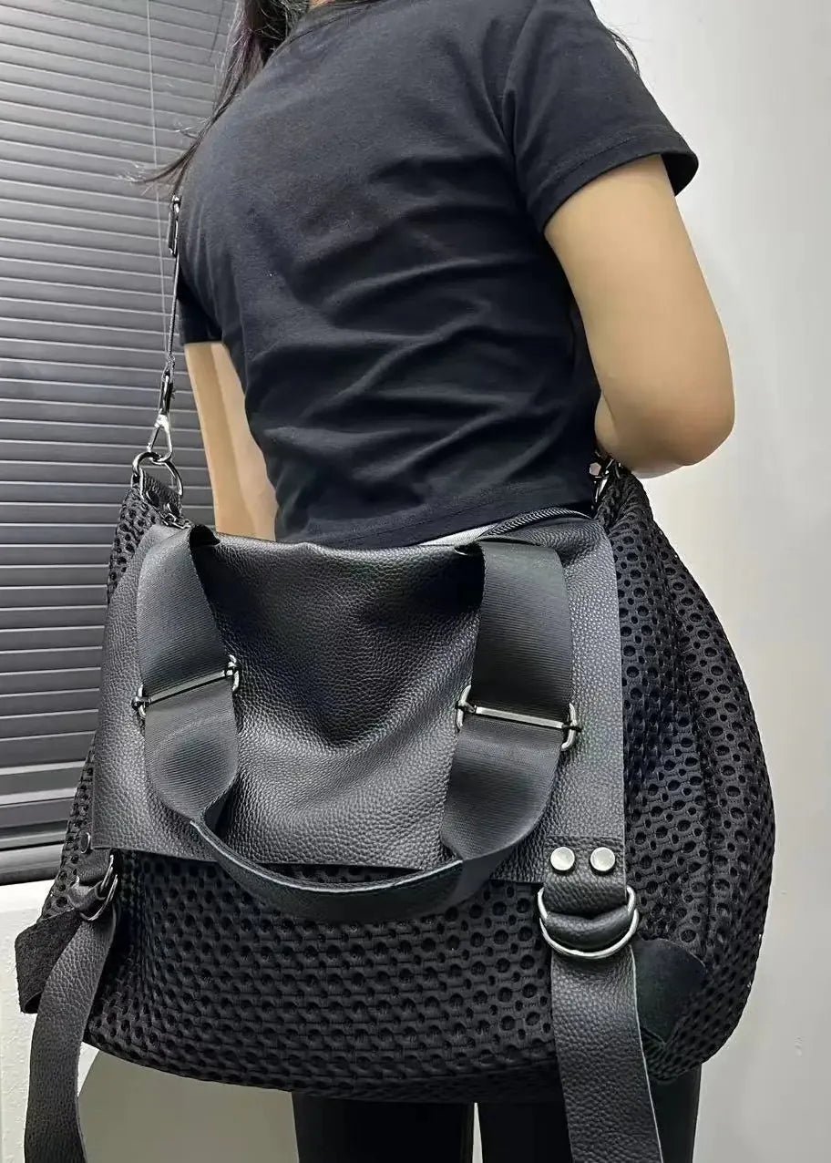 Person wearing a black textured backpack against a neutral background