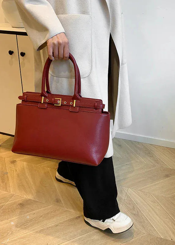 Person holding a red handbag on a wooden floor