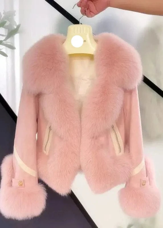 Pink fur coat with large fox fur trim on a hanger against a neutral background