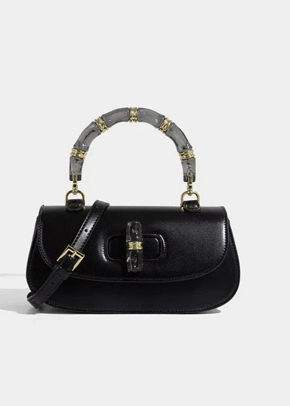 Black handbag with decorative handle on a light gray background