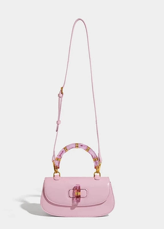 Pink handbag with a decorative handle on a light gray background