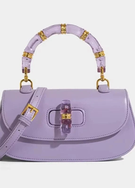 Lavender handbag with gold accents on a light gray background
