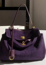 Purple handbag with gold accents on a white surface