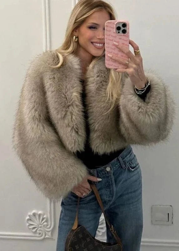 Woman taking a mirror selfie wearing a fur coat and jeans.