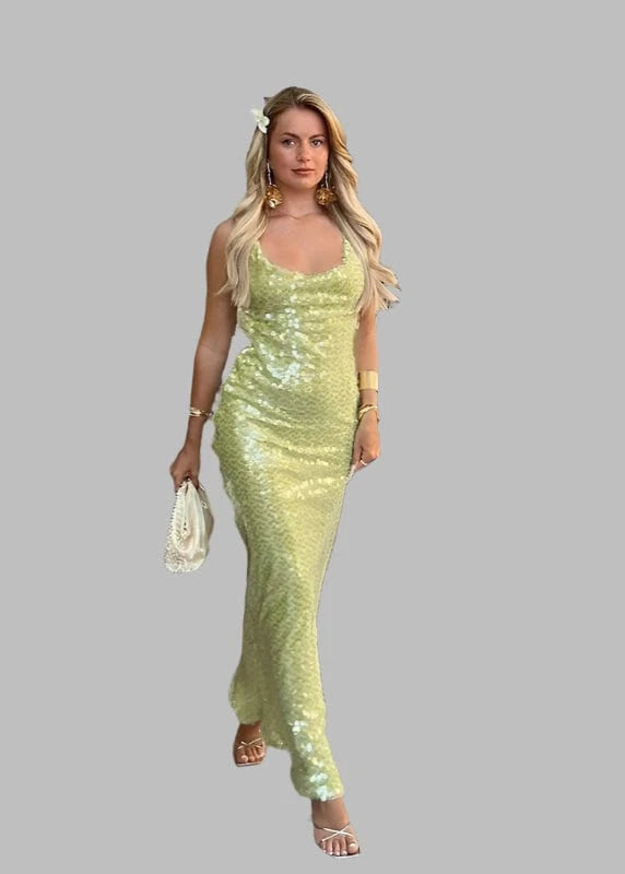 Woman in a green sequin dress standing in a modern outdoor cafe.