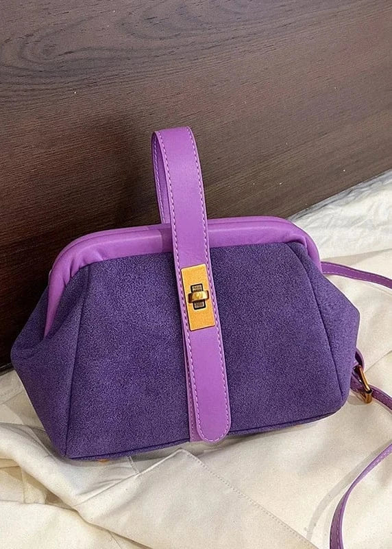 Purple handbag with a matching strap on a textured surface