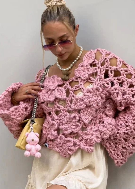 Woman wearing a pink crochet sweater against a plain background