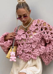 Woman wearing a pink crochet sweater against a plain background