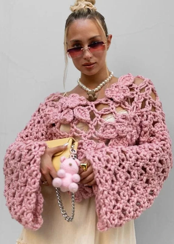 Woman wearing a pink crochet cardigan with a neutral background
