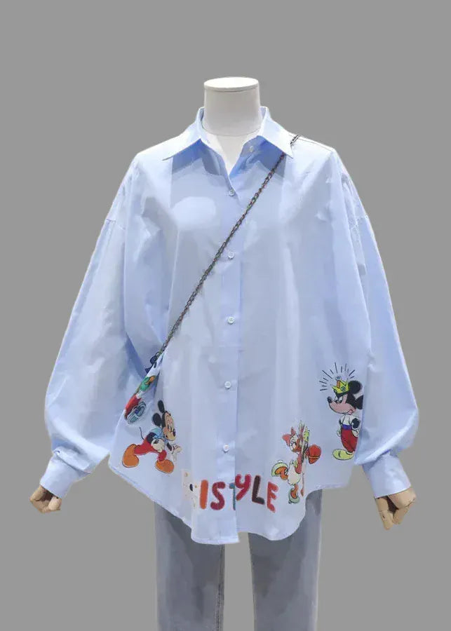 Mannequin wearing a light blue shirt with cartoon character designs in an indoor setting.