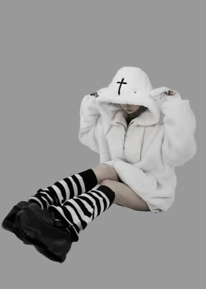 Person wearing a white hoodie with a black cross design, striped socks, and black boots on a white background.