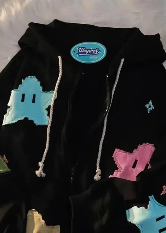 Black hoodie with colorful geometric shapes on a textured surface