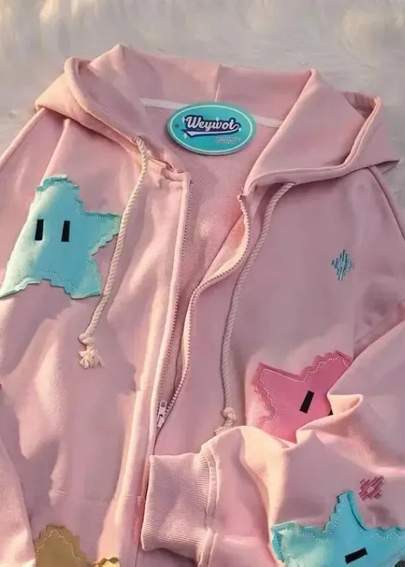 Pink hoodie with colorful patches on a fluffy white background