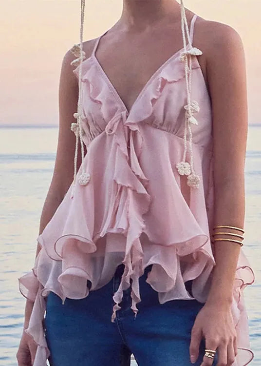 Woman wearing a pink ruffled top with a blurred beach background