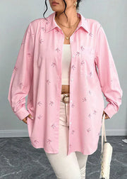 Person wearing a pink shirt with bow patterns on a neutral background