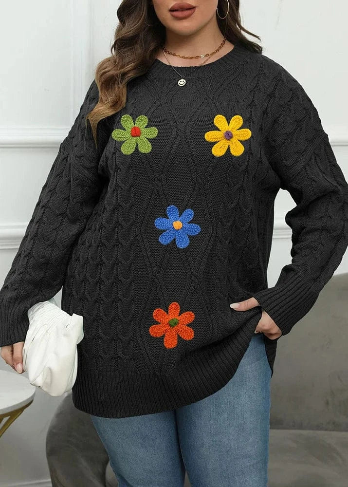 Person wearing a black sweater with colorful flower patterns against a white wall.