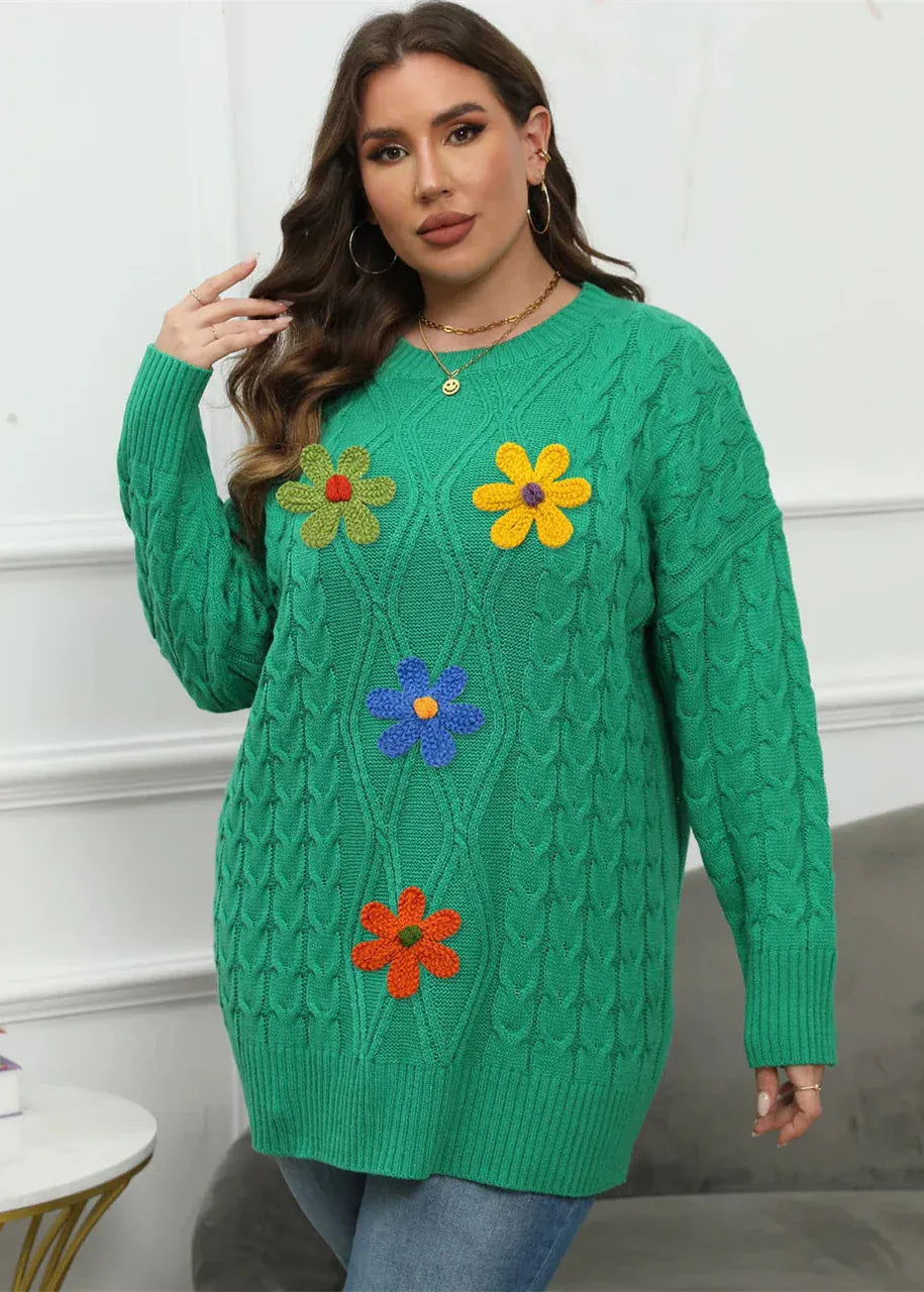 Woman wearing a green sweater with colorful flower patterns against a white wall.