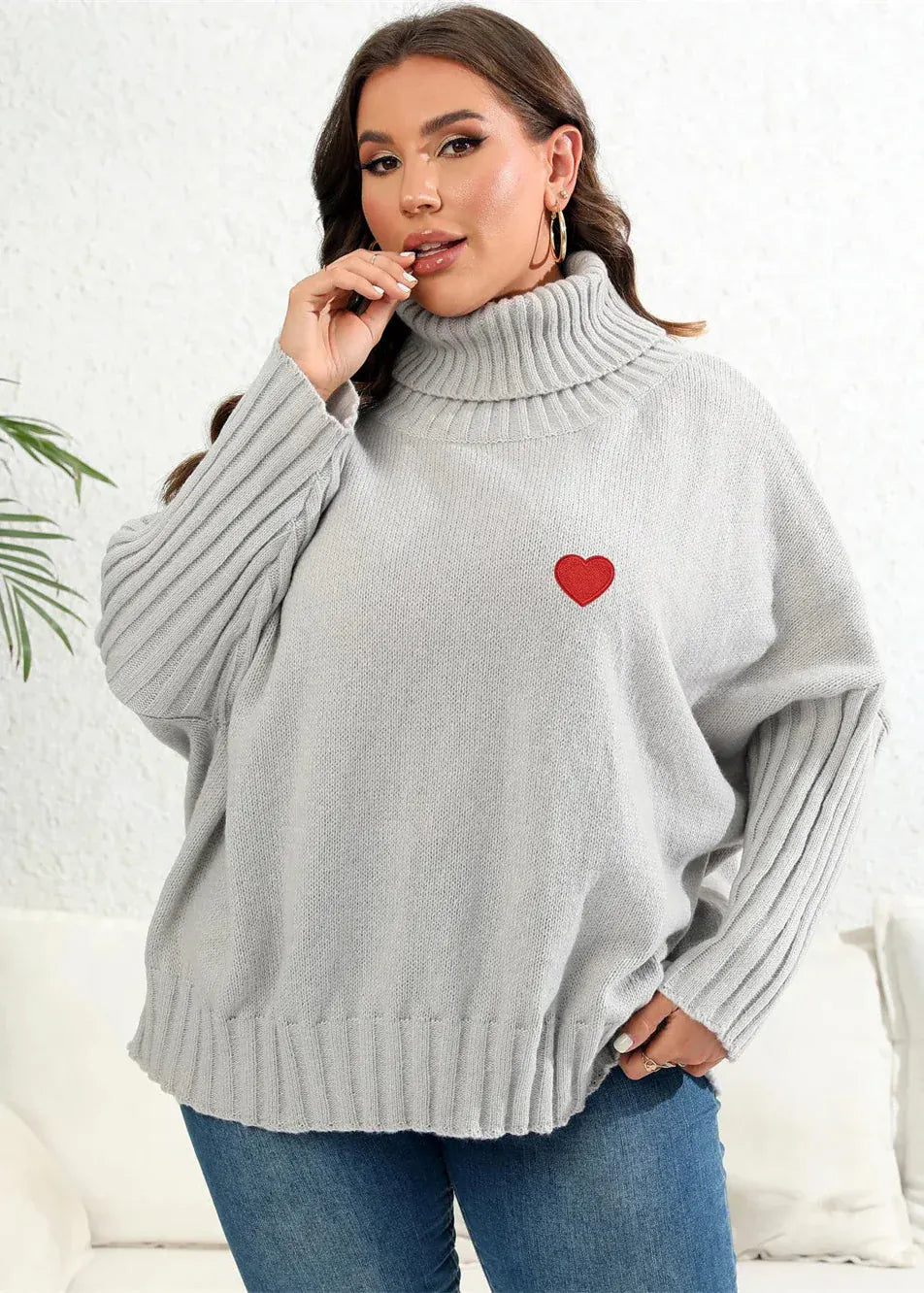 Woman wearing a gray sweater with a red heart design on a white background