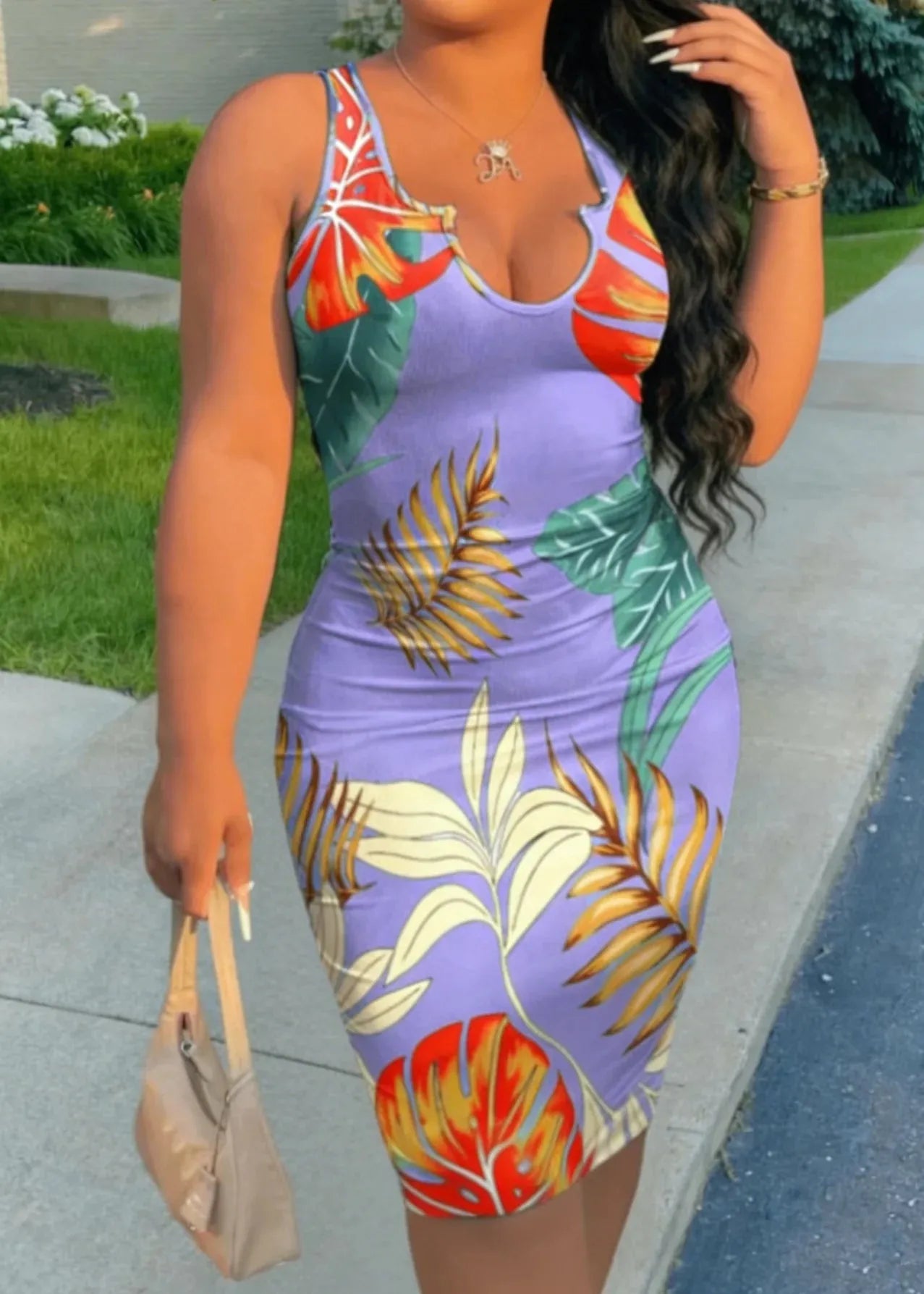 Woman wearing a colorful floral dress with a purple base, standing outdoors.