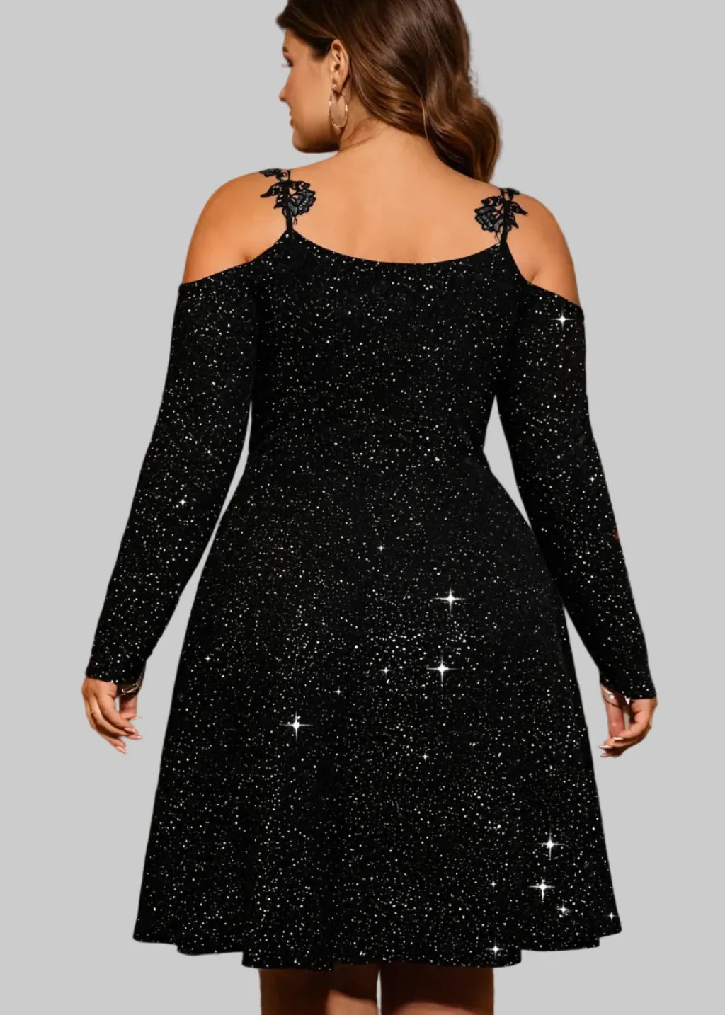 Woman wearing a black sparkly dress in an elegant room with candles and a chandelier.