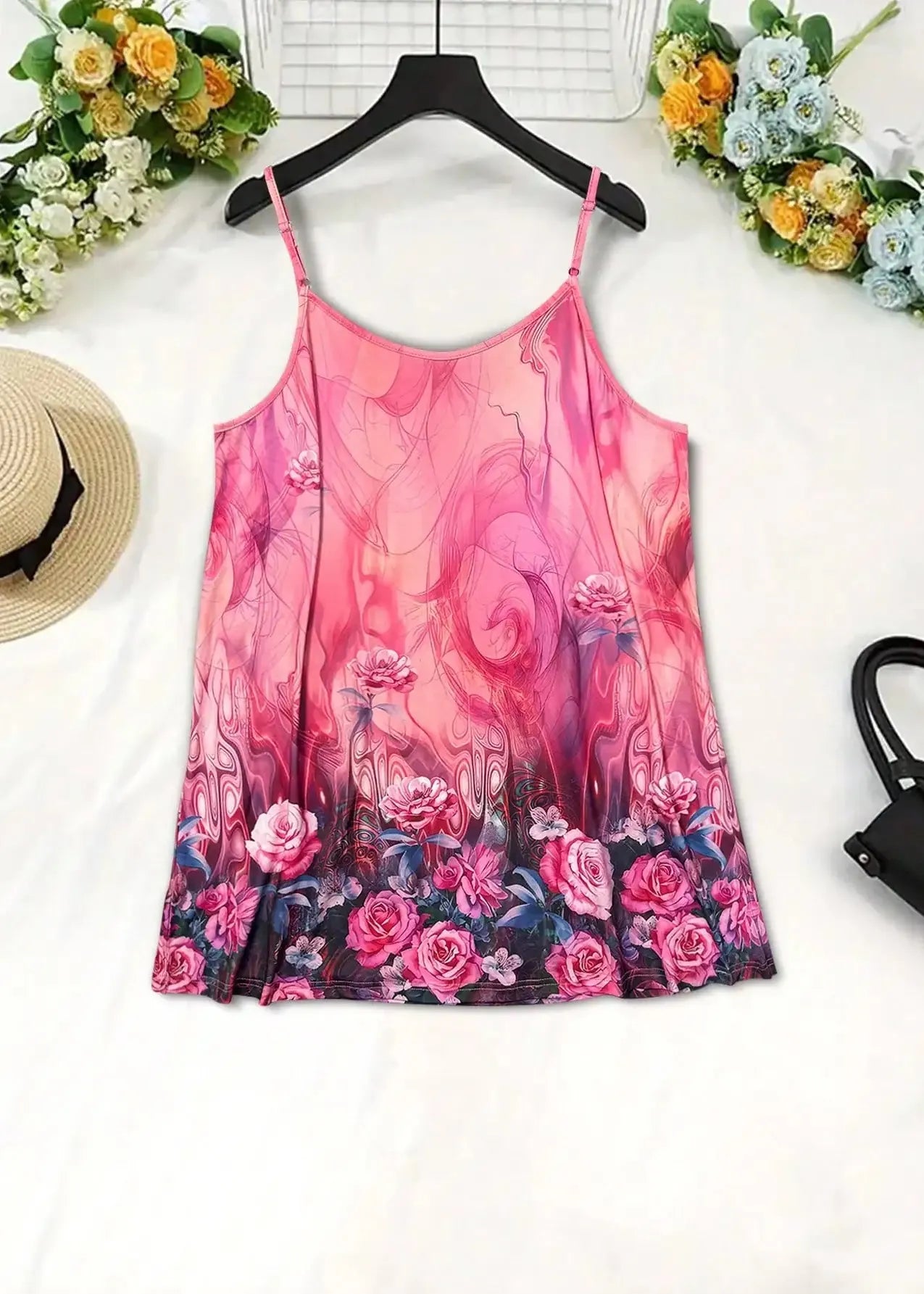 Pink floral dress on a hanger with flowers and a hat in the background