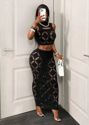 Person wearing a black geometric patterned outfit in front of a white door.