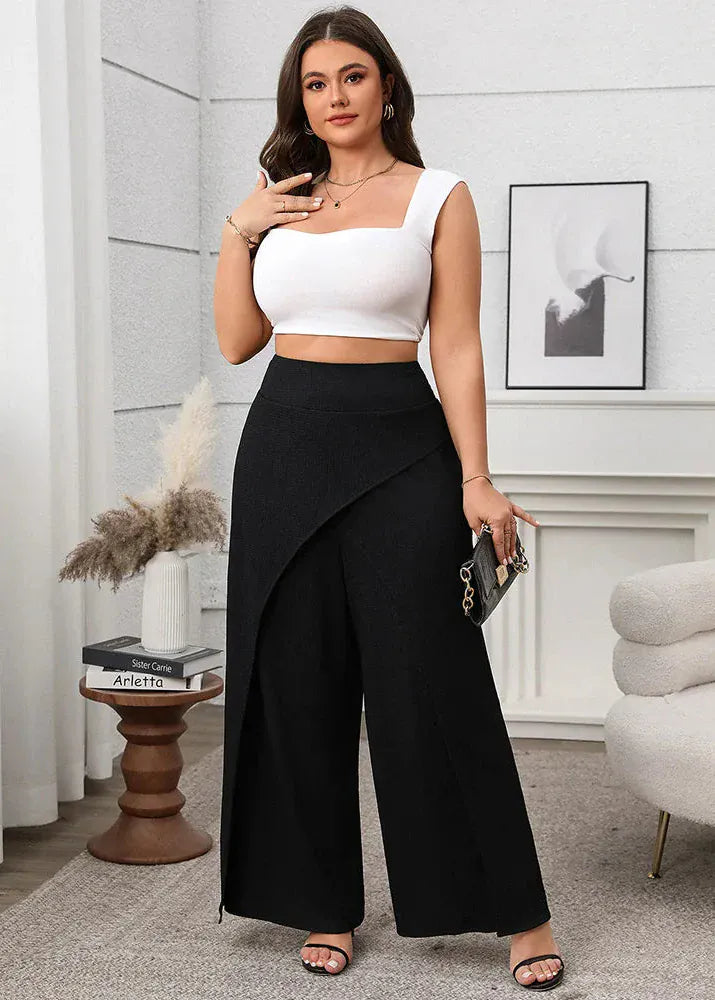 Woman wearing a white top and black wide-leg pants in a room with decor elements.