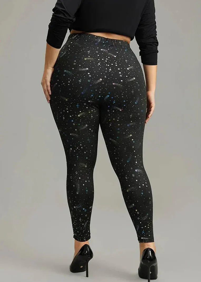 Person wearing black leggings with star pattern on a plain background