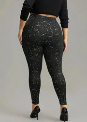 Person wearing black leggings with star pattern on a plain background